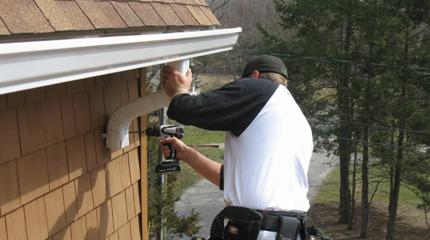 Professional contractor installing tan vinyl siding panels on a residential home exterior in Columbus, GA